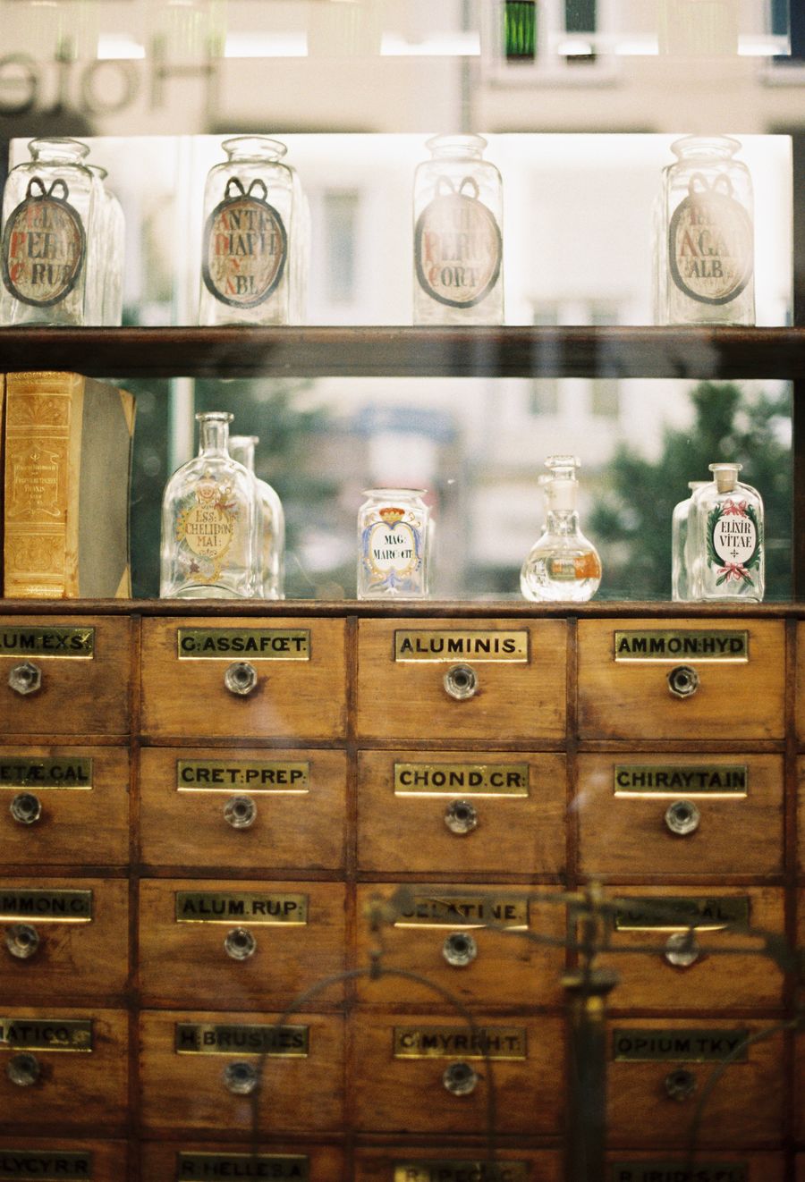 Antique wooden apothecary cabinet filled with labeled glass bottles and drawers — the kind of curious goods found at Madam Zed's Emporium