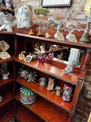 Close-up of Madam Zed's Emporium — antique figurines, handcrafted tonics and Victorian treasures on wooden shelving