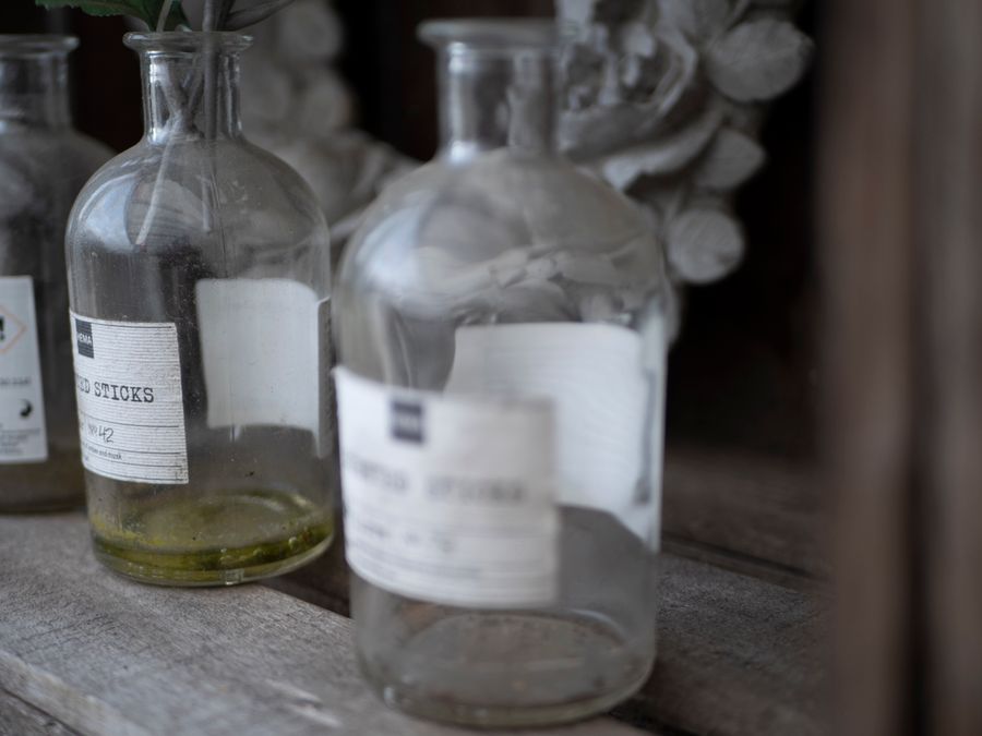 Collection of dusty vintage glass apothecary bottles on a rustic wooden surface