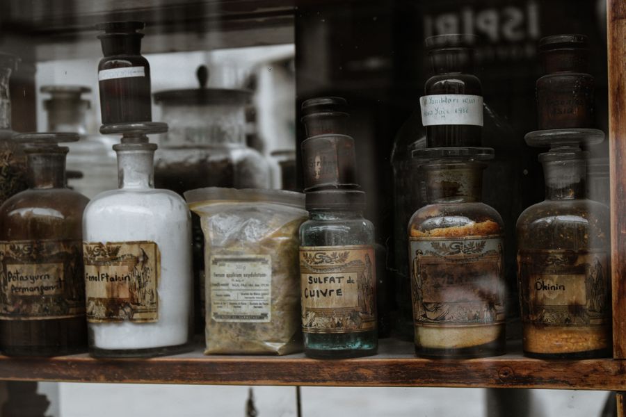 Vintage apothecary bottles with handwritten labels arranged on a wooden shelf