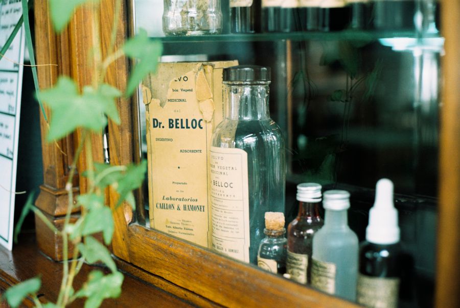Collection of vintage apothecary glass bottles displayed in a wooden cabinet