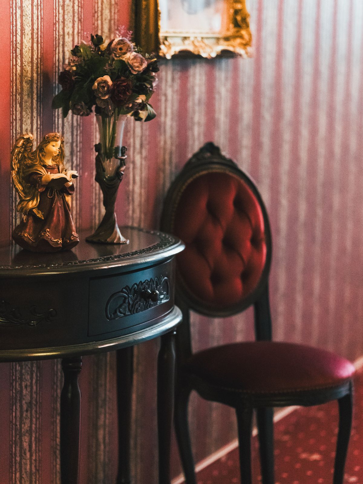 Elegant Victorian interior decor with angel figurine, floral arrangement, and ornate vintage furniture