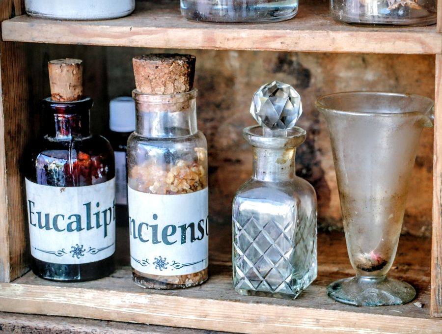 Vintage apothecary bottles on a rustic wooden shelf — the kind of curious remedies found at Booth 69